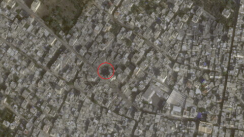 A satellite image of a dense urban area with a red circle around a crater.
