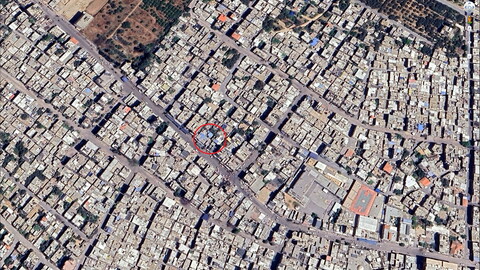 A satellite image of a dense urban area with a red circle around a specific building.