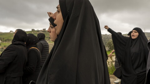 With fists raised high, the women walk by the Zionist military site of Al-Abbad, denouncing America and ‘Israel.’ March 6, 2024. Houla, South Lebanon. (Fatima Joumaa/The Public Source)