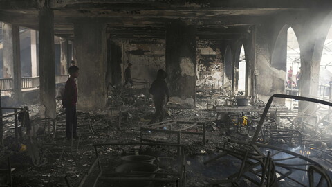 Children walk through the charred remains of what was once a school.