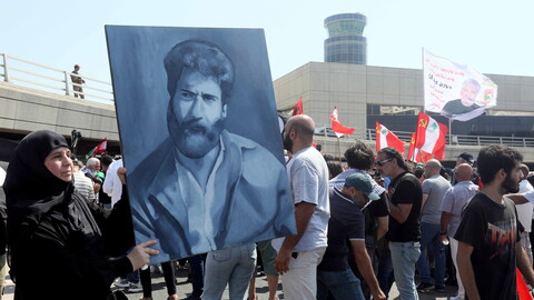 A woman holds a painting of former political prisoner Georges Abdallah outside of the Rafik Hariri Airport in Beirut, Lebanon.