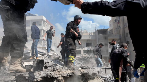 Civil Defense and other responders join forces to rescue people trapped under the rubble following the Hay al-Raml/al-Raml neighborhood strike in Sur. A Civil Defense member’s hand is seen taking a cellphone from another, as people check on one another in the aftermath of the strike. It is one of more than 160 strikes—the largest Israeli wave of fire attacks on the country since the beginning of the genocidal campaign on Palestine and Lebanon in October 2023. 