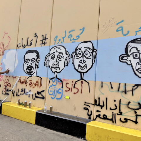فنان غرافيتي يرسم جدارية لبعض أوليغارشيي لبنان على حائط نُصب قرب ساحة رياض الصلح في وسط بيروت. ٢٤ تشرين الأول ٢٠١٩. (لارا بيطار، مصدر عام)