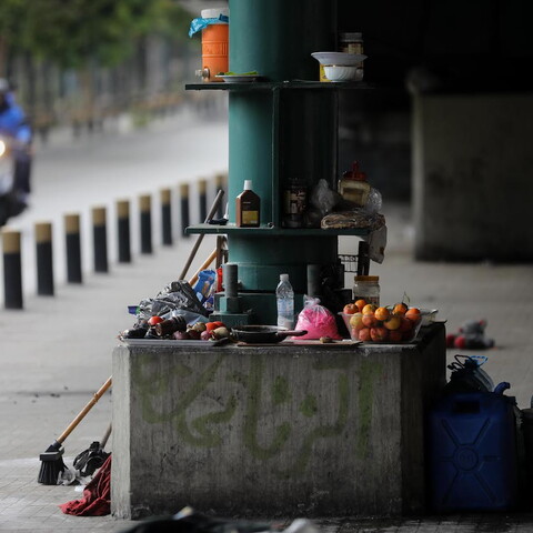 Bruised fruits and kitchen utensils are laid around the green metal column of the Fiat bridge in Beirut.