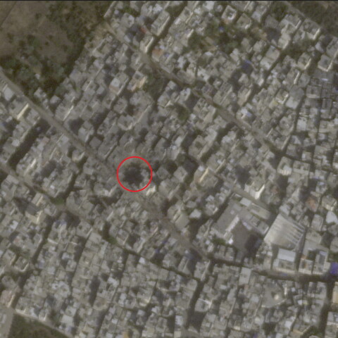 A satellite image of a dense urban area with a red circle around a crater.