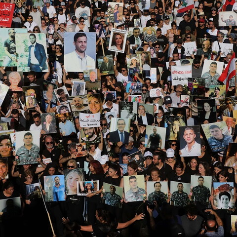 A large crowd of thousands of people walking together, carrying posters and photos.