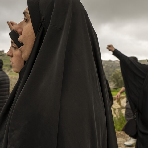 With fists raised high, the women walk by the Zionist military site of Al-Abbad, denouncing America and ‘Israel.’ March 6, 2024. Houla, South Lebanon. (Fatima Joumaa/The Public Source)