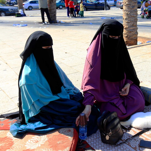 Two displaced women sit with their cat on the streets of Beirut. 