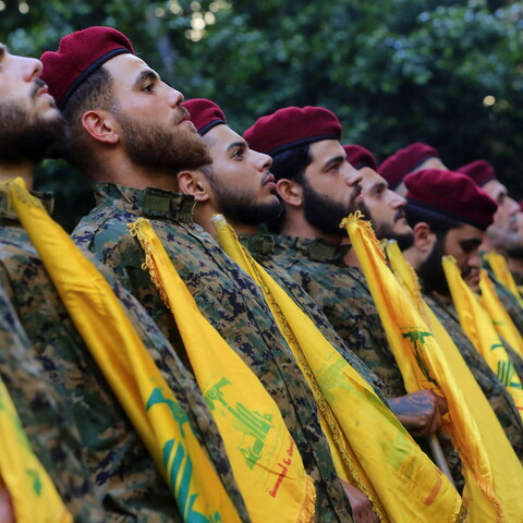 Hezbollah fighters stand at attention with flags