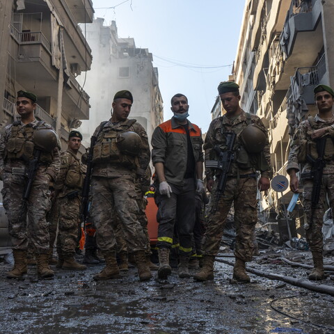 جنود من الجيش اللبناني وعنصر من الدفاع المدني يقفون أمام المبنى المستهدف في شارع فتح الله. بيروت، لبنان. ٢٣ كانون الأول، ٢٠٢٤. (مصدر عام، فاطمة جمعة)