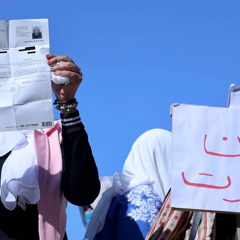 A group of women holding up signs to the camera. One of them reads "We are dying" in Arabic.