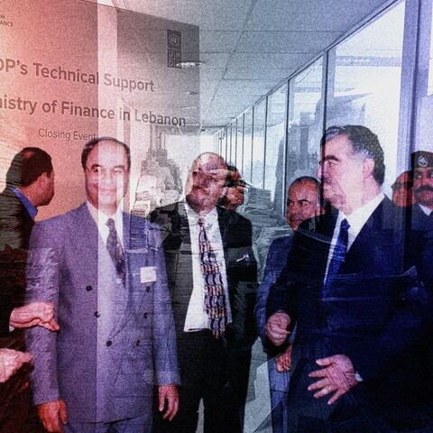 A composite photo. A group of five men in suits are huddled together in the foreground deep in discussion. In the background is a hallway with stacks of loose papers, merged with a large poster that reads: "UNDP's Technical Support to the Ministry of Finance in Lebanon: Closing Event."