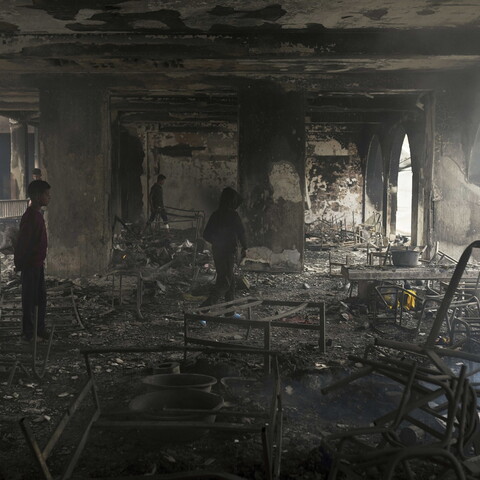 Children walk through the charred remains of what was once a school.