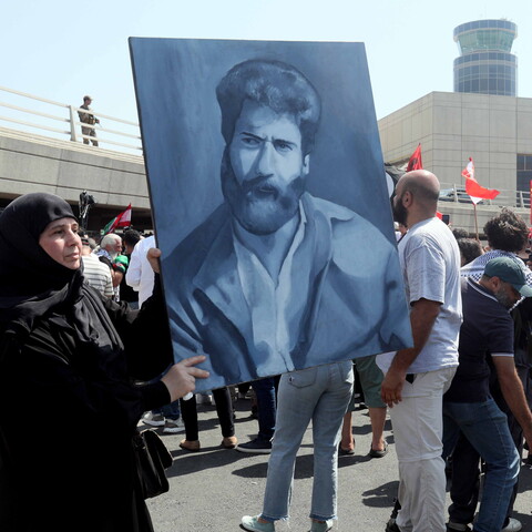 A woman holds a painting of former political prisoner Georges Abdallah outside of the Rafik Hariri Airport in Beirut, Lebanon.