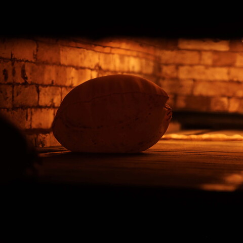 A loaf of Arabic bread inflates inside an oven. Fire seen in the background.