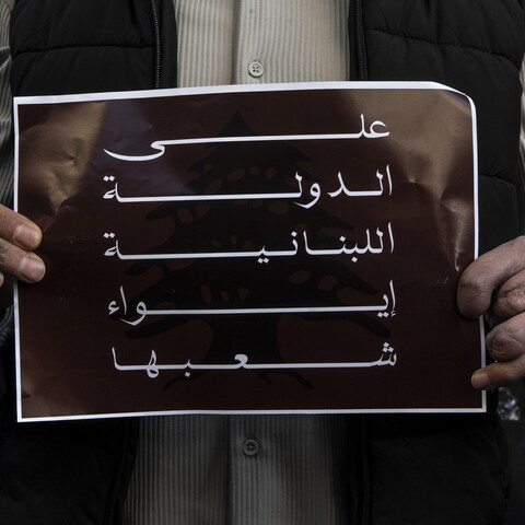 A survivor of the Israeli pager attack holds up a poster that reads: “The Lebanese state must shelter its own.”
