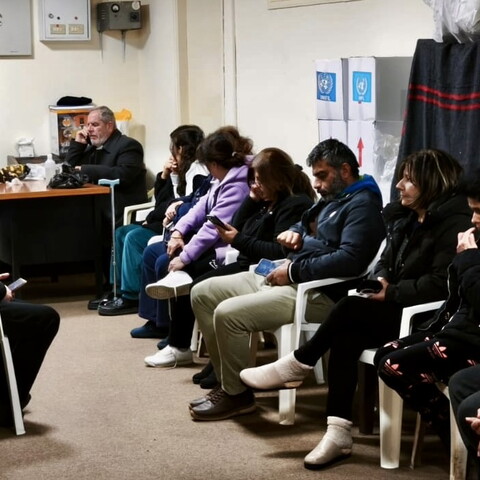 Town residents gather around the church hall with Father Maroun Ghafari. 