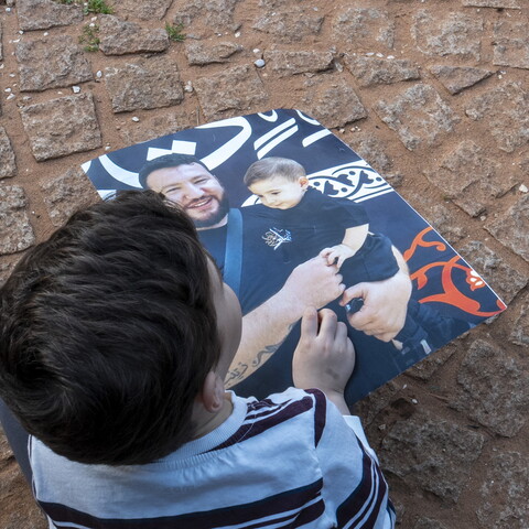 A child holding a photo of a man carrying a child. 