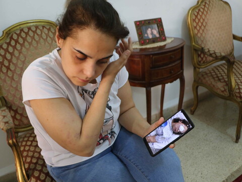 ميرنا، البالغة من العمر ٣٦ عامًا، في بيتها في الكرنتينا. يظهر هاتفها صورتها في المستشفى بعد الانفجار. فقد كل من ميرنا وجارها إيلي عينًا بسبب الانفجار. الكرنتينا، بيروت. ٣ أيار ٢٠٢١. (رولا خياط/مصدر عام)