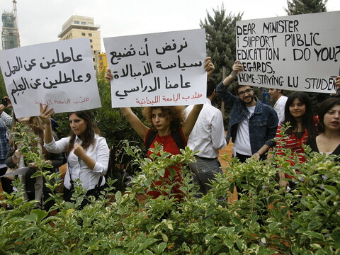 Lebanese University students holding cardboard signs join a protest in solidarity with their professors' strike.