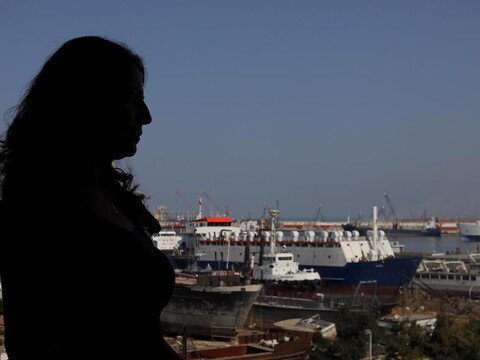 Silhouette of a woman looking over Tripoli's seaport