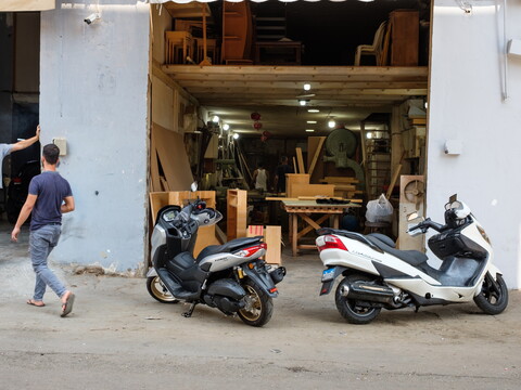 Motorcycles parked outside a small carpentry workshop in the industrial zone