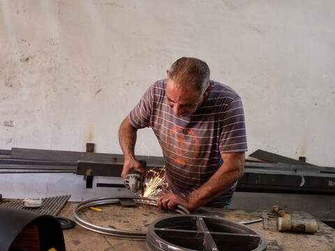 Iron worker cuts a steel piece in his steel workshop