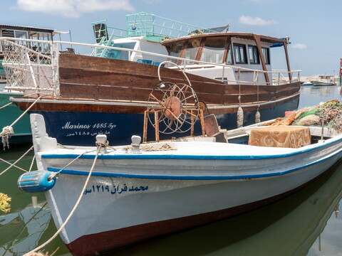 Two fishing vessels sit side by side in a port. 