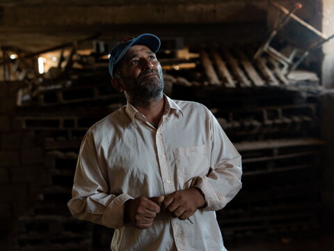 A farmer stands inside his empty barn.