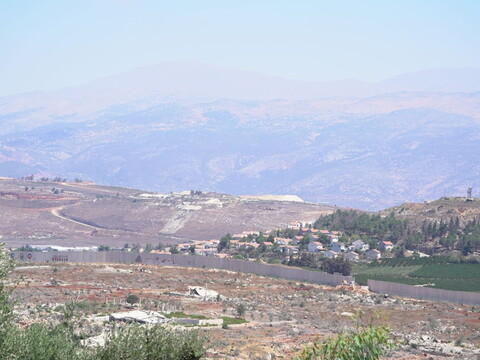 The destroyed village of Kfar Kila with the Blue Line border wall and Metulla settlement visible in the distance.