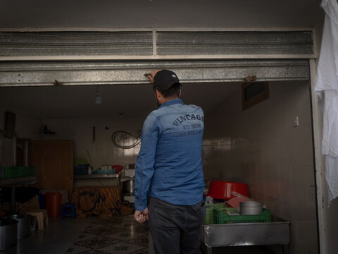  Farmer Khodor Zahra lifts the metal shutter of his small dairy factory in Chebaa.