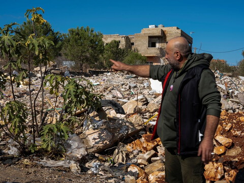 A man points to a pile of rubble marking the site where a car was targeted by an Israeli strike.