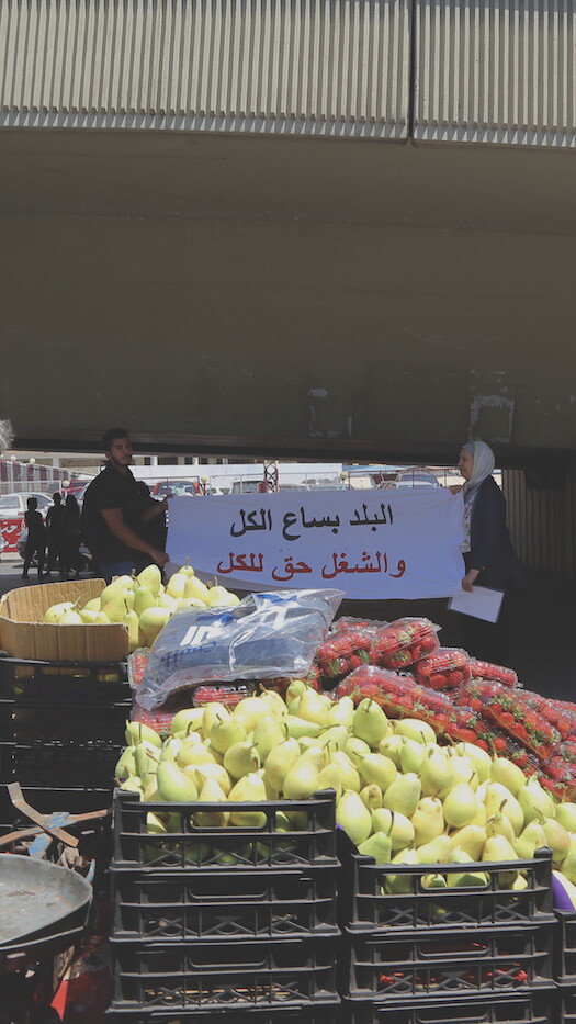 بائع متجوّل يمرّ بالقرب من تظاهرة ضدّ حملة وزارة العمل على العمالة الأجنبية في بيروت. ٣٠ تمّوز ٢٠١٩. (حسين بيضون، مصدر عام)