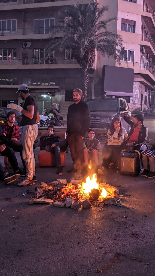 متظاهرون يتحلقون حول النار بعد ليلة من تسكير جادة فؤاد شهاب، المعروفة بإسم جسر "الرينغ"، في بيروت، ٢٨ تشرين الثاني ٢٠١٩. (لارا بيطار، مصدر عام)