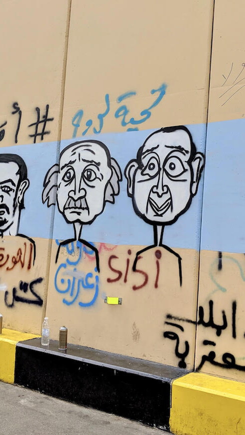 فنان غرافيتي يرسم جدارية لبعض أوليغارشيي لبنان على حائط نُصب قرب ساحة رياض الصلح في وسط بيروت. ٢٤ تشرين الأول ٢٠١٩. (لارا بيطار، مصدر عام)