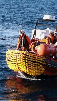 A dinghy at sea. A rescue worker in the foreground.