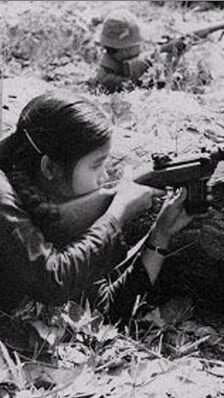A black-and-white photo features a southern Vietnamese female guerrilla fighter pointing her rifle with determination, embodying the resilience of those who fought for their homeland.