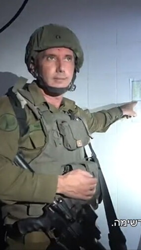 A screenshot of a video where Israeli military spokesperson Daniel Hagari is seen pointing at a paper on the wall behind him. The paper contains a table: a calendar.