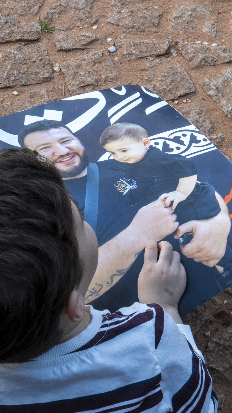 A child holding a photo of a man carrying a child. 