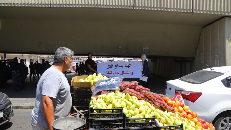 A street cart vendor passes by a protest near the Lebanese Ministry of Labor in Beirut against crackdowns on unregulated labor, July 30, 2019. (Hussein Baydoun/The Public Source)