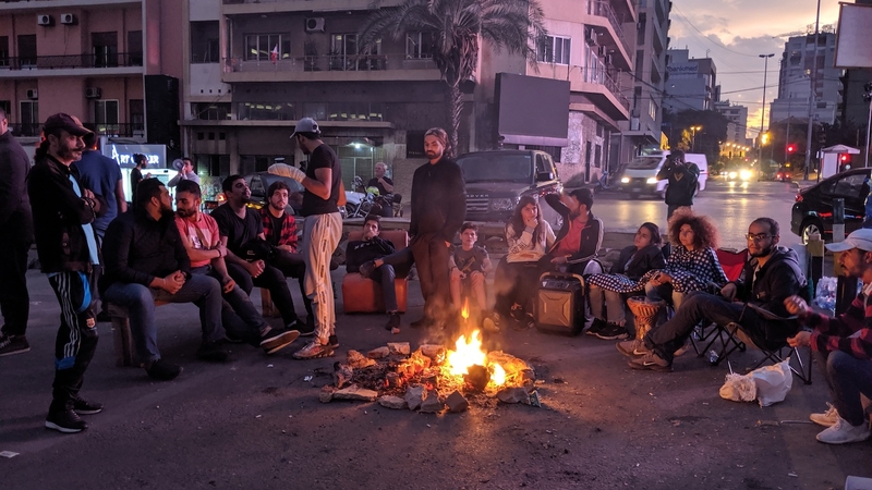 Protestors gather around a bonfire at dawn, after having spent the night blocking Fouad Chehab Ave., commonly referred to as the "Ring Bridge," in Beirut. October 28, 2019. (Lara Bitar/The Public Source)