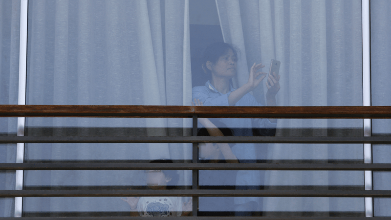 A migrant domestic worker films a May Day march as it passes by her employer's home. Beirut, Lebanon. May 1, 2020. (Marwan Tahtah/The Public Source)