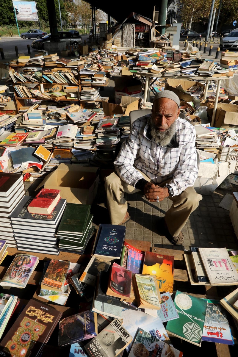 Mohammad Maghrebi sits among the piles of books he has collected for his open-air bookstore. 