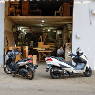 Motorcycles parked outside a small carpentry workshop in the industrial zone