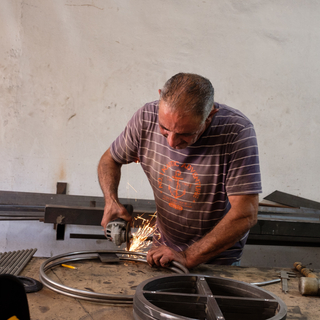 Iron worker cuts a steel piece in his steel workshop