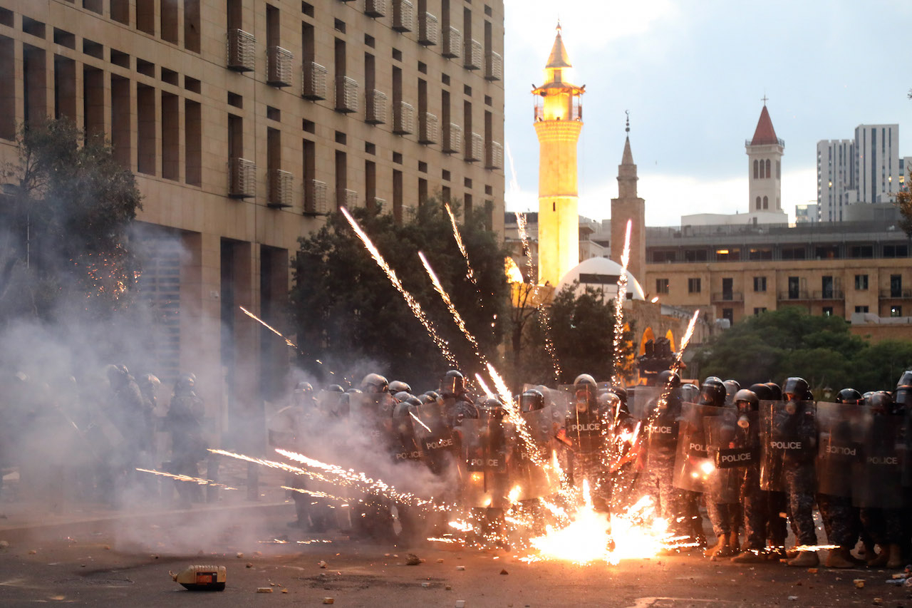 Protestors lob firecrackers at riot police in downtown Beirut.