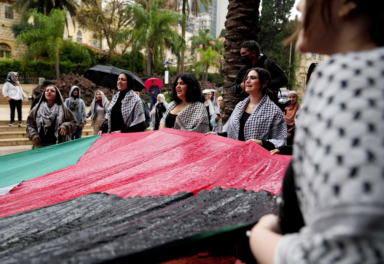 Student protesters hold a large Palestinian flag