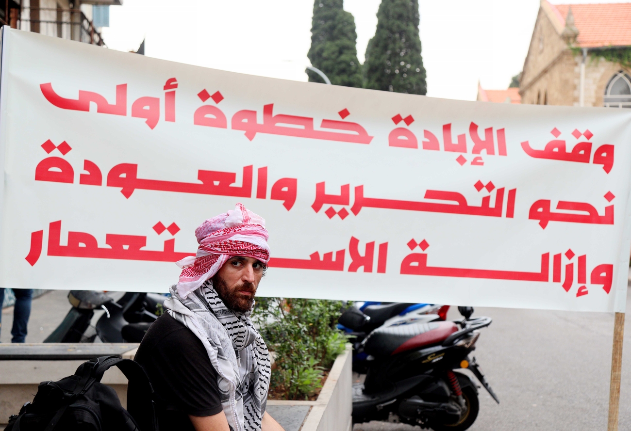 A man sits in front of a protest banner