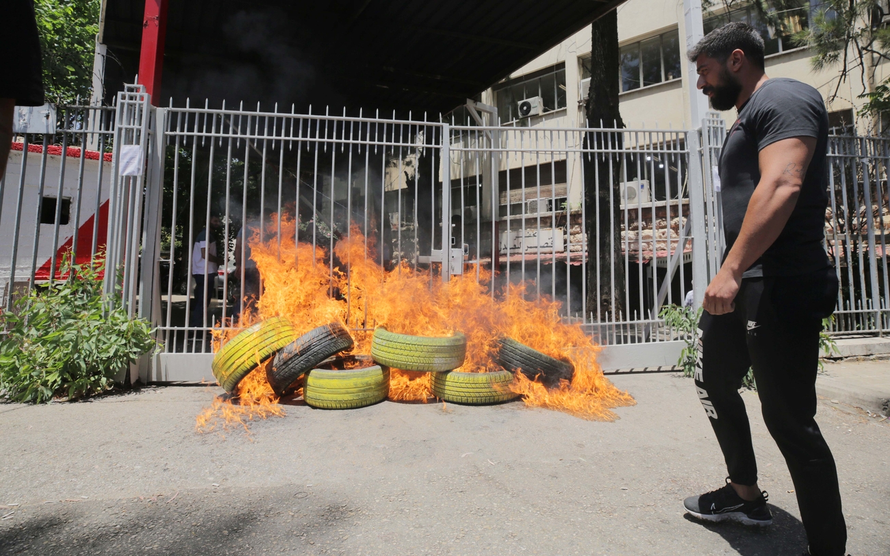 Man stands next to burning tires