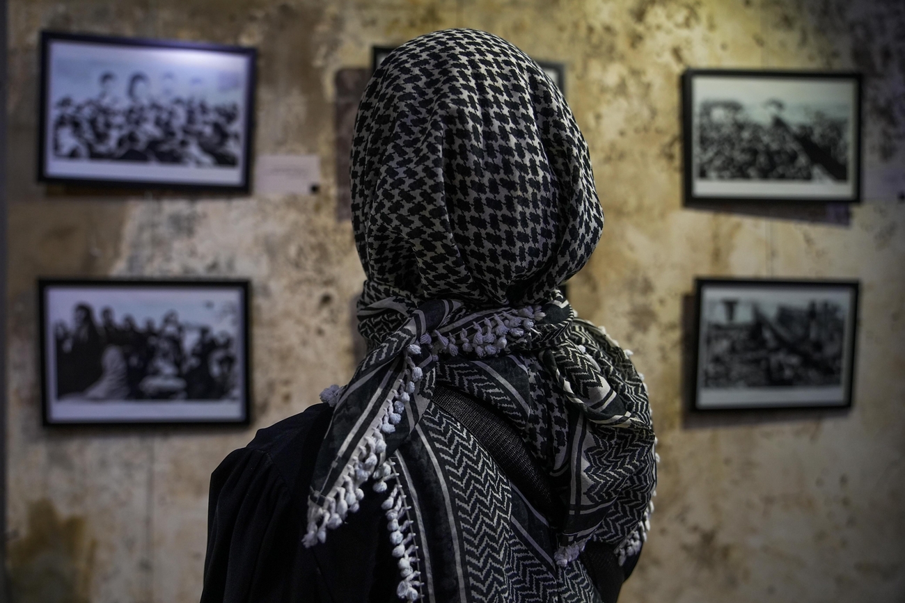 Woman wearing keffiyeh looks at photographs